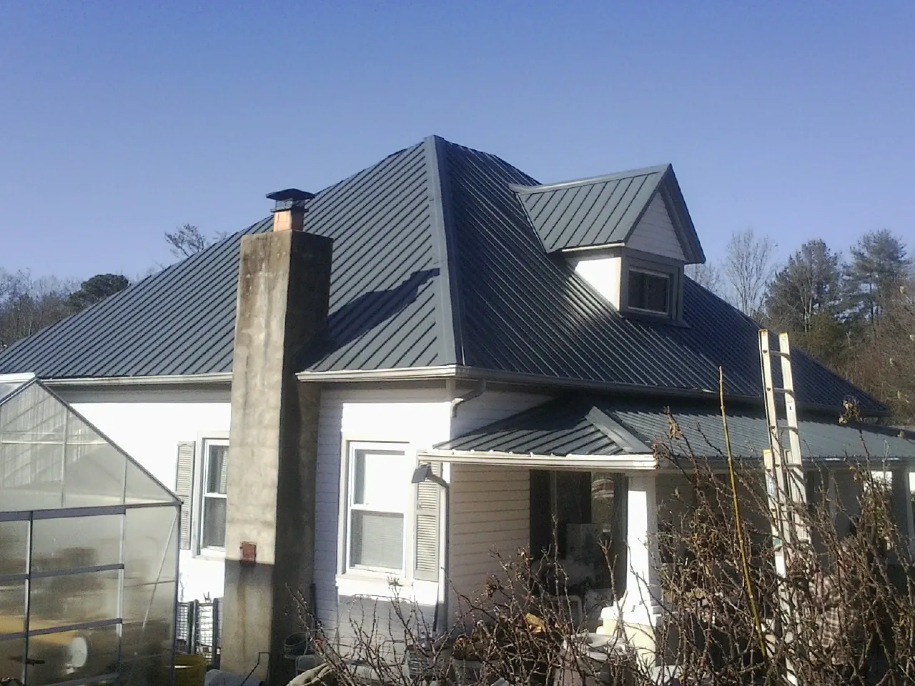 Dark blue standing seam metal roof on a white farmhouse with dormer — Slate & Tile Roof Repair by Roofing Brothers in White Plains