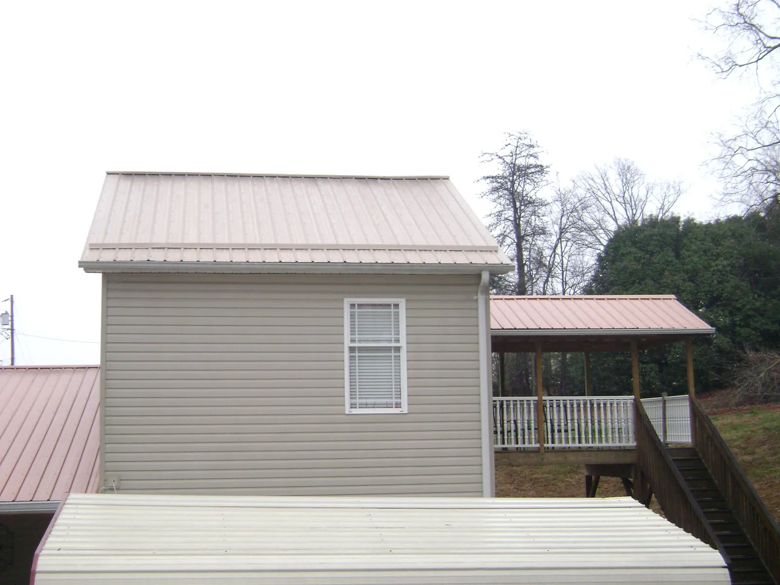 Tan metal roofs on a two story addition and attached porch, from a Roof Replacement job in White Plains