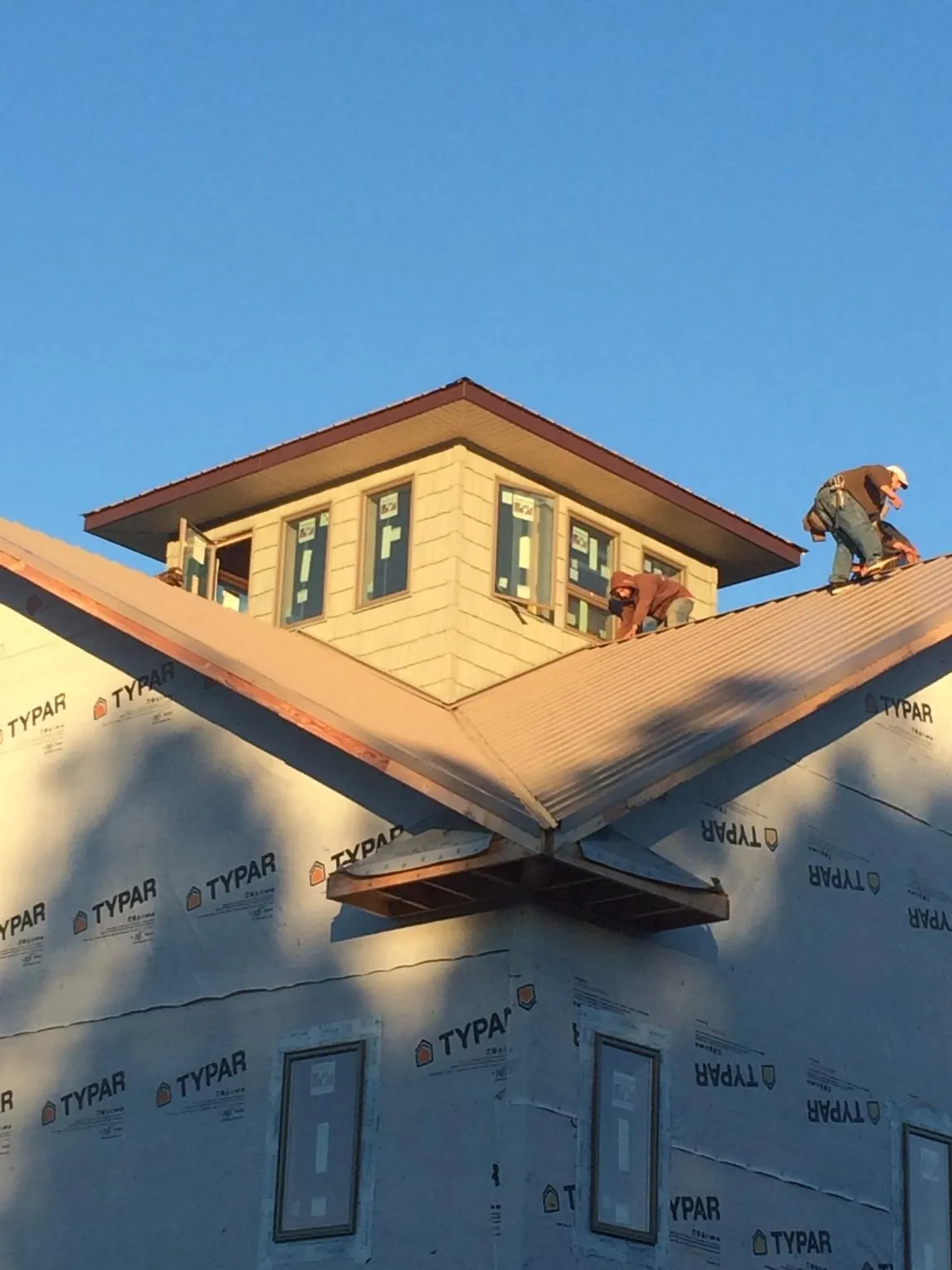 Roofers working around a rooftop cupola on a new metal roof at sunset — Roof Waterproofing in White Plains by Roofing Brothers